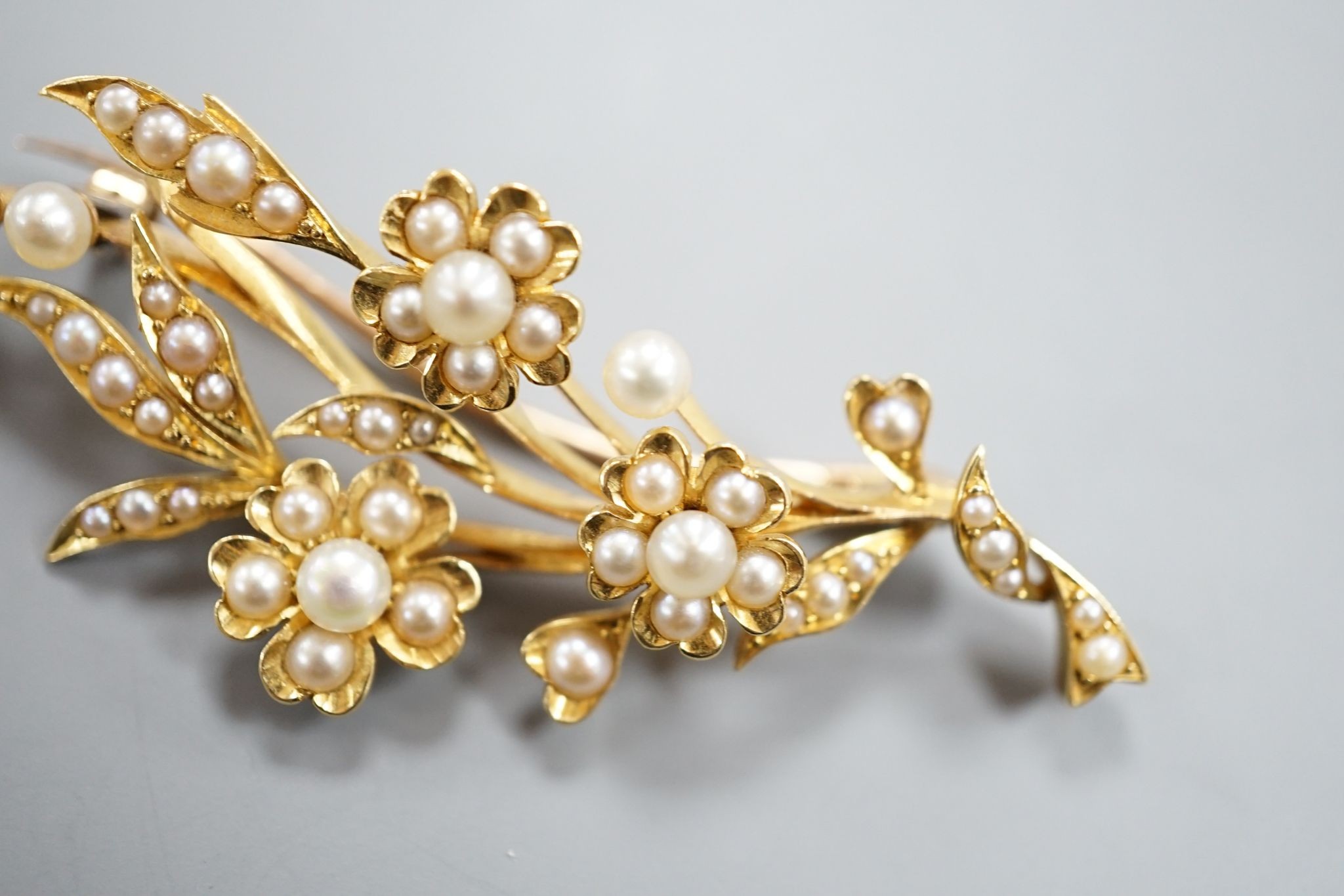 An Edwardian yellow metal and seed pearl set spray brooch, 58mm, gross weight 8.7 grams.